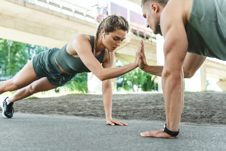 Athletic couple and fitness training outdoors. Man and woman doing push-ups exercise.