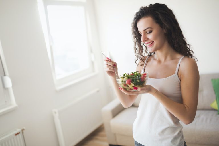 Beautiful fit woman eating healthy salad