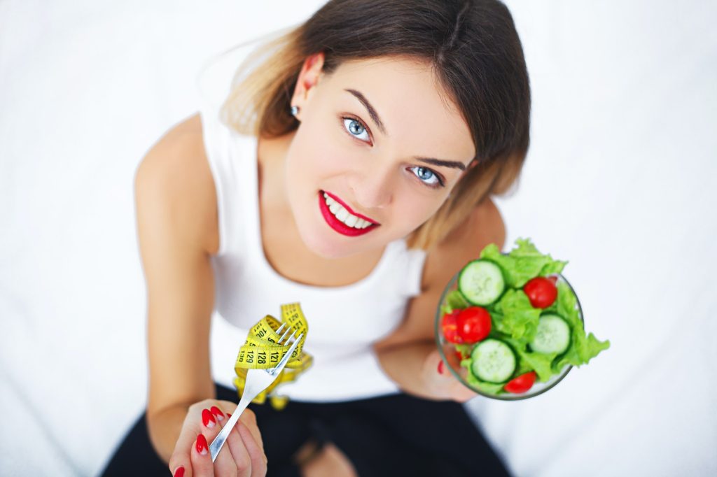 Beautiful Woman On Healthy Diet With Organic Green Vegetable Salad In Kitchen.