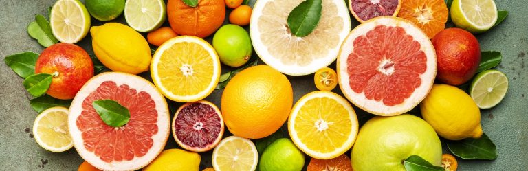 Citrus fruit food background, top view. Mix of different whole and sliced fruits