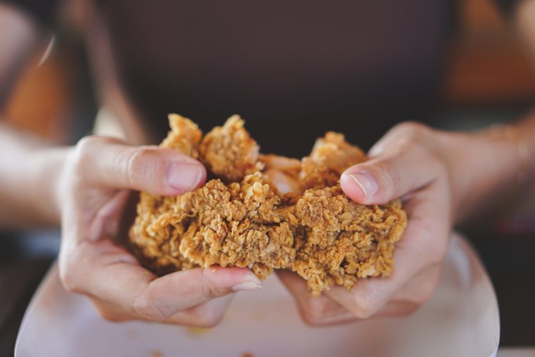 close up focus woman hand hold and showing fried chicken meal for eat at restaurant bar,fast food co
