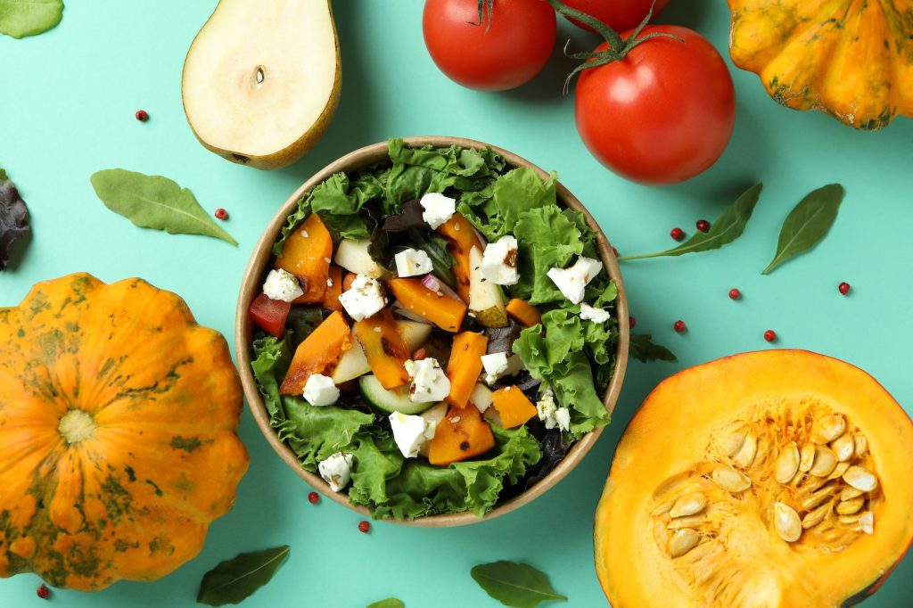 Concept of healthy food with pumpkin salad on mint background