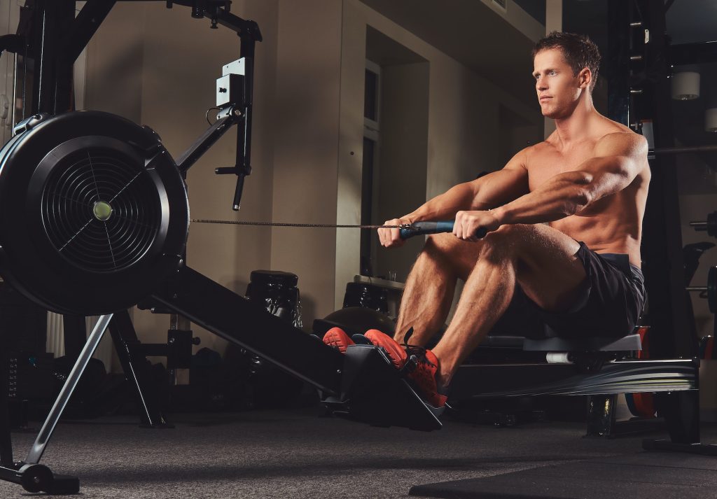 Handsome muscular fitness male doing exercise on the rowing machine.