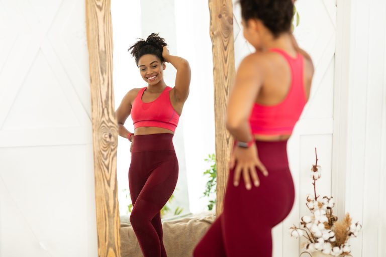 Joyful Black Lady After Weight Loss Posing Near Mirror Indoors