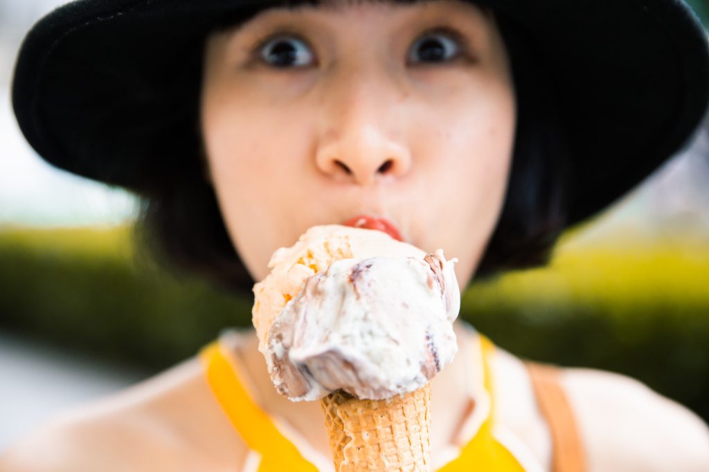 Outdoor closeup fashion portrait of young hipster eating ice cream.