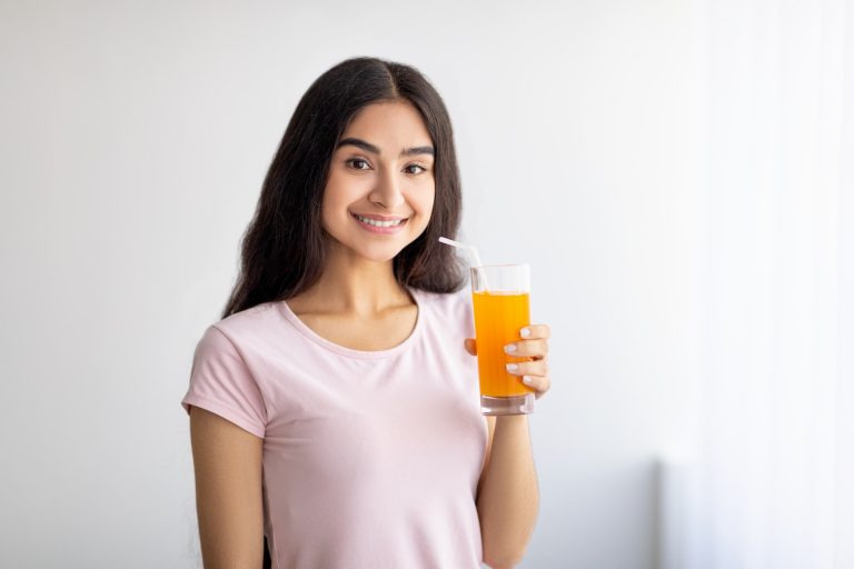 Pretty Indian woman drinking fresh fruit juice, enjoying detox beverage at home, copy space. Healthy