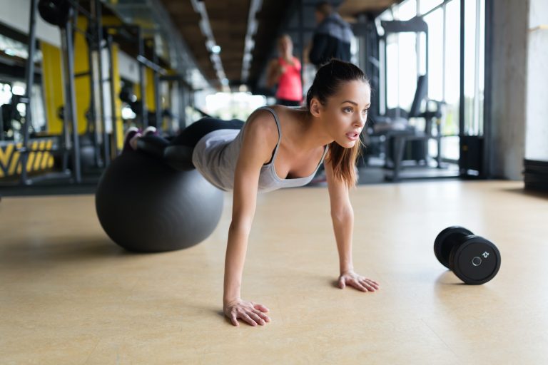 Young woman exercising with swiss ball in gym