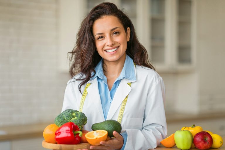 Portrait of smiling female nutritionist with plate of fresh fruits, working at weight loss clinic